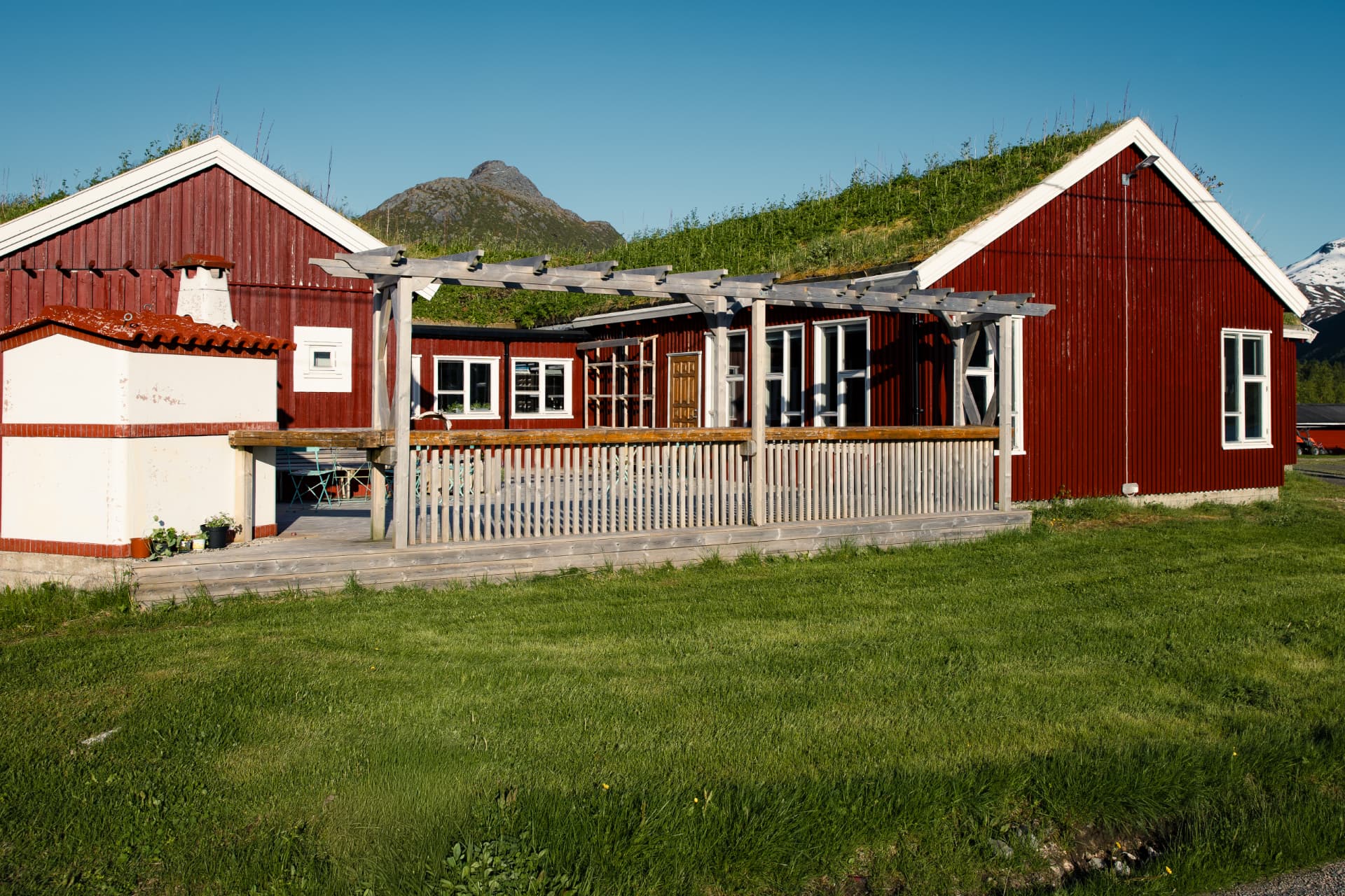 Tunet på Livland Gård i sommerlys, med røde hus og torvtak